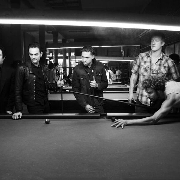 Photograph of members of the band Queens of the Stone Age playing pool